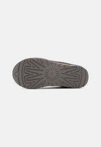 Semelle de chaussure en caoutchouc gris texturé avec un motif radial et un talon renforcé pour l'adhérence et la durabilité.