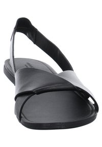 Mustat ja harmaat tasapohjat sandaalit, joissa on ristikkäinen nahkaremmi ja ohut nilkkaremmi, jossa on tarrakiinnitys.