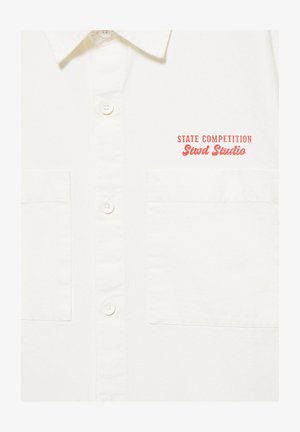 Biała koszula na guziki z dwoma przednimi kieszeniami i czerwonym tekstem „STATE COMPETITION Stwd Studio” po lewej stronie na wysokości klatki piersiowej.