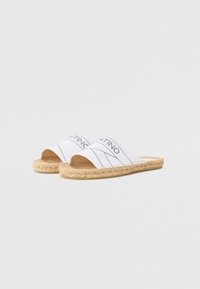 White espadrille slides with open toes. Cotton upper features thin black stripes and branding. Natural jute sole with stitched edge details.