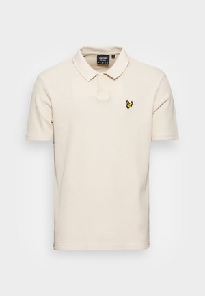 Beiges Polohemd mit kurzen Ärmeln, zwei Knöpfen und einem kleinen gelben Vogel-Logo auf der linken Brust.