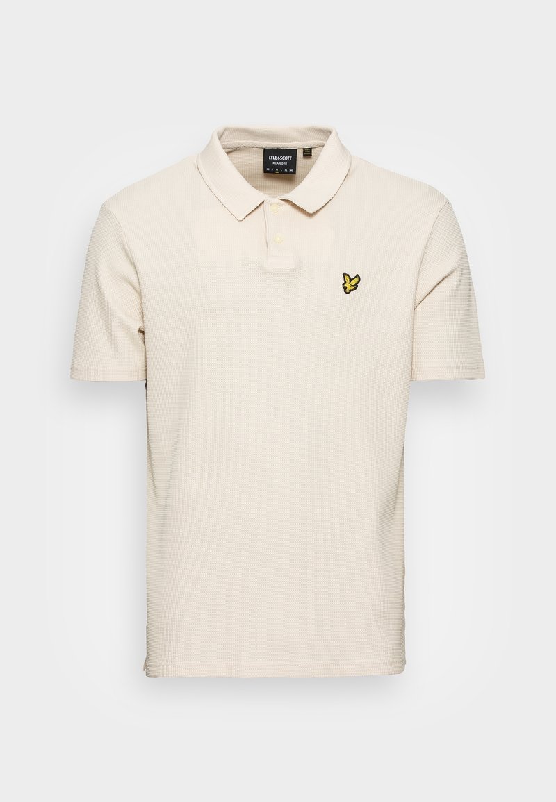 Polo beige à manches courtes avec deux boutons et un petit logo d'oiseau jaune sur la poitrine gauche.