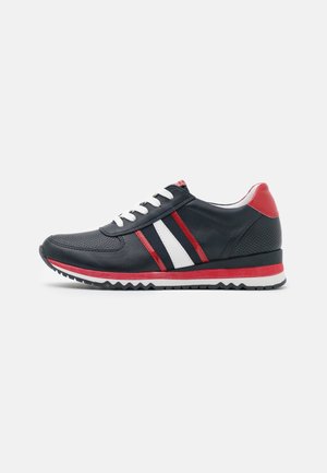 Sort sneaker med hvide snørebånd, røde og hvide side striber, rød hæl accent og en rød og hvid lagdelt sål på hvid baggrund.