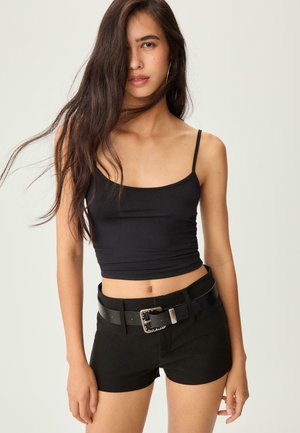 Black crop top made of a stretchy fabric, paired with high-waisted black shorts. Notable silver hardware on a wide belt. Smooth texture.