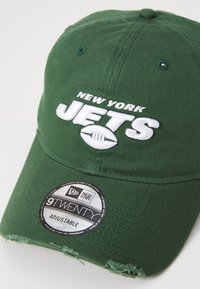 Grønn justerbar baseballcaps med brodert "NEW YORK JETS"-logo i hvitt og slitt brem. New Era 9TWENTY-merkelapp inkludert.