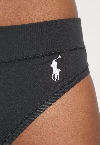 Melns kokvilnas bikini ar plašu elastīgu jostu, sānos ar baltu izšūtu logotipu un plakanām šuvēm, lai nodrošinātu ērtumu.