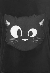 Felpa nera con una grande grafica di un volto stilizzato di gatto in bianco, con occhi grandi, baffi e orecchie dettagliate. Tessuto morbido.