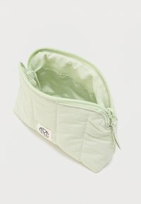 Φωτεινό πράσινο ραμμένο ύφασμα θήκη με φερμουάρ μισάνοιχτο, που αποκαλύπτει κενό εσωτερικό και ένα μικρό ορθογώνιο λογότυπο στο πλάι.