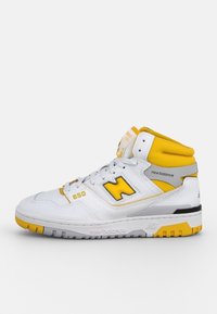 Sneaker alta con tomaia in pelle bianca, dettagli gialli, dettagli perforati e suola nera. Presenta il marchio "New Balance".