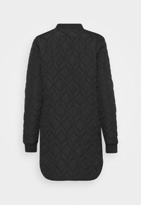 Veste longue noire matelassée avec surpiqûres en forme de diamant, poignets côtelés et col droit vue de dos sur fond blanc.