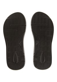 Semelles de chaussures en caoutchouc noir arborant un motif en chevrons, une forme courbée et un marquage bien visible sur le côté.