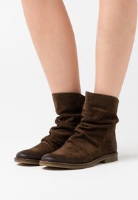 Ruske suedes ankle čizme sa snižim dizajnom, okruglim vrhom i ravnim gumiranim đonom. Teksturirana površina s mekim završetkom.