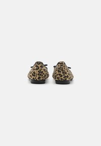 Ballerine con stampa leopardata caratterizzate da un motivo beige e nero, punta rotonda, materiale simile al cuoio e suola nera, con un'accattivante decorazione a fiocco.