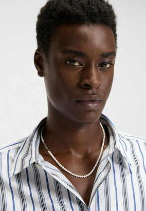 White and blue striped shirt with a collar, featuring a pearl necklace. Smooth texture, slim fit, and button details are visible.
