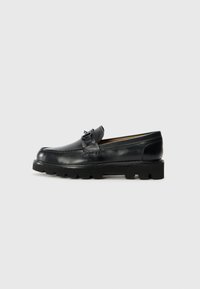 Black leather loafers with a rounded toe, decorative buckle accent, and textured rubber sole. Smooth surface with contrast stitching details.