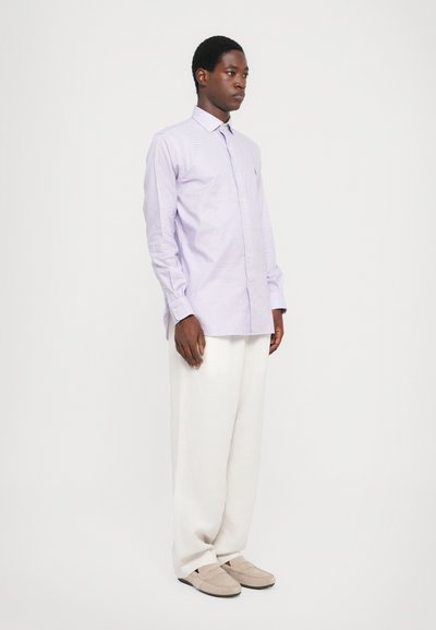 Cămașă butonată cu carouri, de culoare violet deschis, cu guler clasic, asociată cu pantaloni albi largi și pantofi slip-on bej.