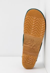 Zielona zamszowa podeszwa z teksturowaną, jasnobrązową gumową podeszwą z wzorem w jodełkę oraz tłoczonym numerem rozmiaru 37.