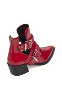 Botines de charol rojo con puntera afilada, que cuentan con múltiples hebillas plateadas y una cremallera lateral, sobre un tacón bajo tipo bloque.
