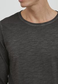 Langærmet, mørkegrå T-shirt i et blødt, struktureret stof med runde halsudskæring og subtile farvevariationer i materialet.