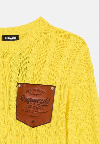 Κίτρινο πλεκτό πουλόβερ με σχέδιο καλώδιου, με καφέ δερμάτινο ταμπελάκι μπροστά με λογότυπο και μεταλλικά καρφιά. Στρογγυλή λαιμόκοψη.