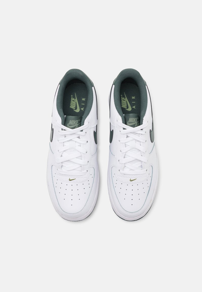 Sneakers bianchi Nike Air con accenti verdi, tomaia in pelle, punta perforata e lacci piatti. Presentano il logo sulla linguetta e sul lato.
