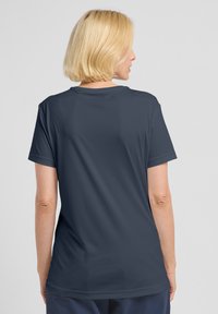 Maglietta a maniche corte di un blu navy scuro con una texture liscia, design a girocollo e una vestibilità rilassata, dotata di maniche arrotolate e un branding minimale.