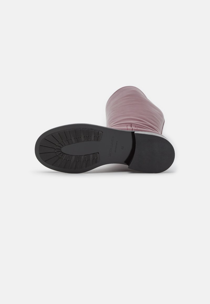 Rosa Leder-Stiefelette mit flexibler Oberseite und einer schwarzen Gummisohle, die über ein strukturiertes Profil für besseren Grip verfügt.