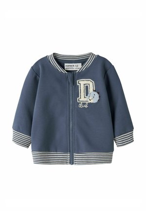 Veste bébé bleue avec poignets et col rayés, fermeture éclair devant, et lettre D brodée avec un petit dinosaure et le texte « club ».