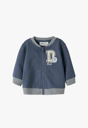Veste bébé bleue avec poignets et col rayés, fermeture éclair devant, et lettre D brodée avec un petit dinosaure et le texte « club ».