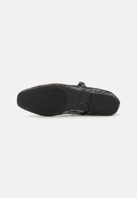 Chaussure noire à lacets avec tige texturée, semelle noire lisse contrastante et coutures visibles le long des côtés.