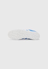 Semelle de basket blanche avec une finition texturée et des accents bleus. Présente trois rayures bleues et une forme lisse et arrondie.