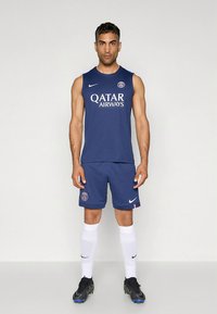 Conjunto atlético azul-marinho composto por uma camisola sem mangas com o logótipo "QATAR AIRWAYS", calções a condizer, meias brancas e sapatilhas de desporto pretas.