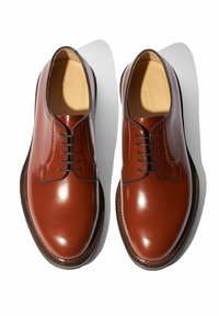 Braune Lederderby-Schuhe mit polierter Oberfläche, Schnürverschluss und runder Zehenform. Mit kontrastierenden Nähten und einer genähten Sohle.