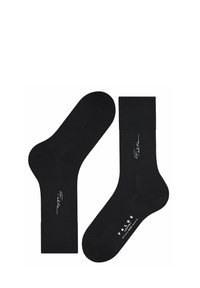 Un paio di calze nere fino al polpaccio con risvolti, caratterizzate dal marchio "Falke" in bianco in corsivo sui lati e in lettere maiuscole sulle suole.