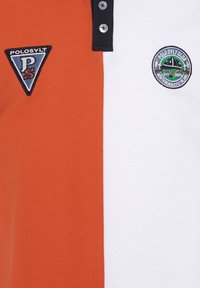 Polo-Shirt mit orangefarbenen und weißen Abschnitten, ausgestattet mit einem schwarzen Kragen, zwei Knöpfen und gestickten Logos in kontrastierenden Farben.