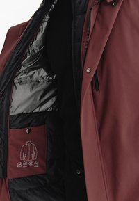 Bordowa kurtka z zamkiem błyskawicznym z przodu, wyposażona w czarne podszycie, kieszeń na przechowywanie z symbolami pielęgnacji oraz gładką, teksturowaną tkaninę.