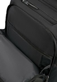Interiörvy av en svart ryggsäck som visar det vadderade facket för laptop och den dragkedjade fickan med diamantmönstrad tygfoder.