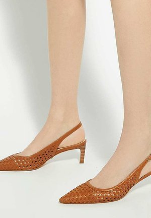 Bruine cut-out slingback hakken met een spitse neus, slanke hak en gestructureerd leer. Beschikt over een verstelbare band en open zijkanten.