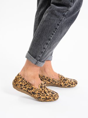 Legs wearing rolled-up dark gray jeans and leopard print moccasin loafers with bow details on a white background.