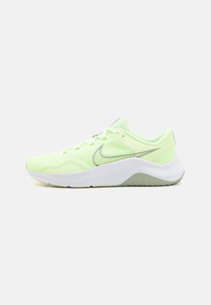 Chaussure de running Nike vert clair avec tige en mesh, logo swoosh gris, semelle blanche épaisse et semelle et talon avec dessin gris.