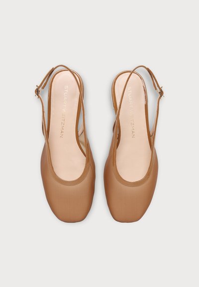 Paire de ballerines beige à bride arrière avec bouts carrés arrondis et brides réglables à boucle sur fond clair uni.