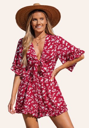 Romper rojo con flores y patrones blancos, con escote en V, lazo en el frente y mangas con volantes. Tejido ligero con un corte relajado y cintura fruncida.
