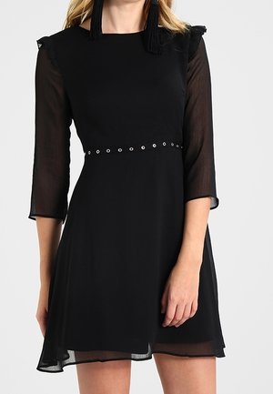 Czarna sukienka z półrękawkami, falbankami i dopasowaną talią. Wyposażona w rząd metalowych, okrągłych oczek w talii. Lekka tkanina.