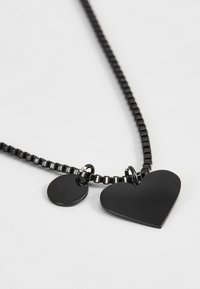 Zwarte ketting met een gestructureerde schakels, met een groot hart en een kleine ronde hanger. Beide hangers zijn glanzend en glad.