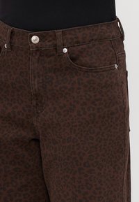 Bruine luipaardprint jeans met een aansluitend ontwerp, voorzien van een rits- en knoopsluiting, voorkzakken en contraststeeksel.