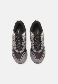 Sport shoes in black and gray with a textured pattern, reflective accents, and black laces. Features a cushioned sole for support.