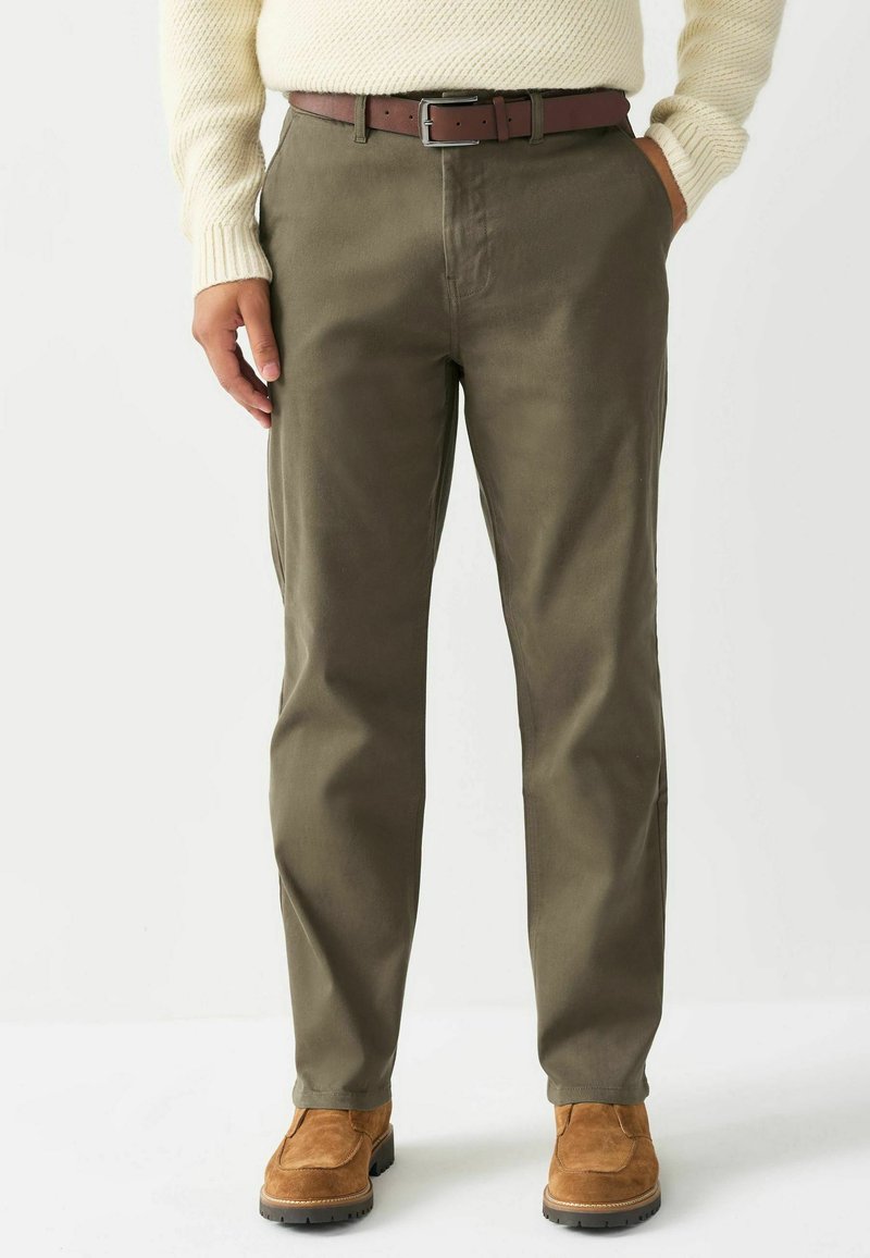 Oliivrohelised püksid, mis on valmistatud pehmest puuvillast, sirge sääre disainiga, küljetaskute ja pruunist nahkvööst, millel on hõbedane sula.