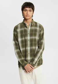 Green plaid long-sleeve shirt with button closure, featuring a lightweight fabric, white accents, and a relaxed fit. Notable for contrasting patterns.