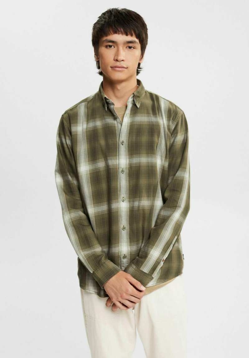 Green plaid long-sleeve shirt with button closure, featuring a lightweight fabric, white accents, and a relaxed fit. Notable for contrasting patterns.
