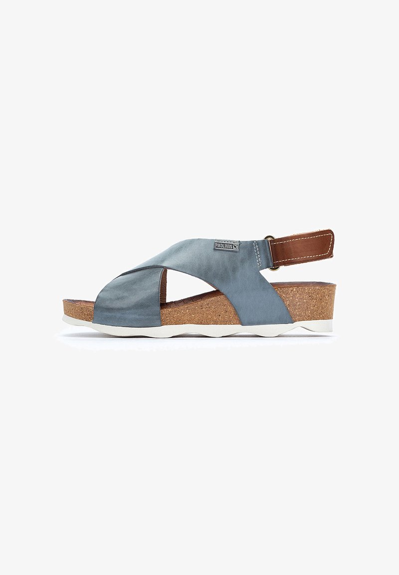 Sandalia de satén azul con tira cruzada, plantilla de corcho, acento en cuero marrón, suela blanca y correa trasera ajustable. Diseño casual con materiales texturizados.
